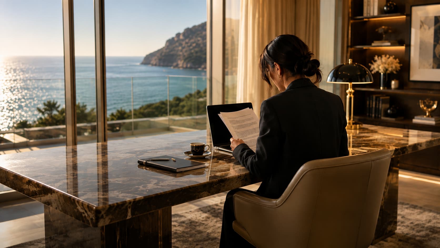 A professional reading a document at a marble desk in a villa study overlooking the sea